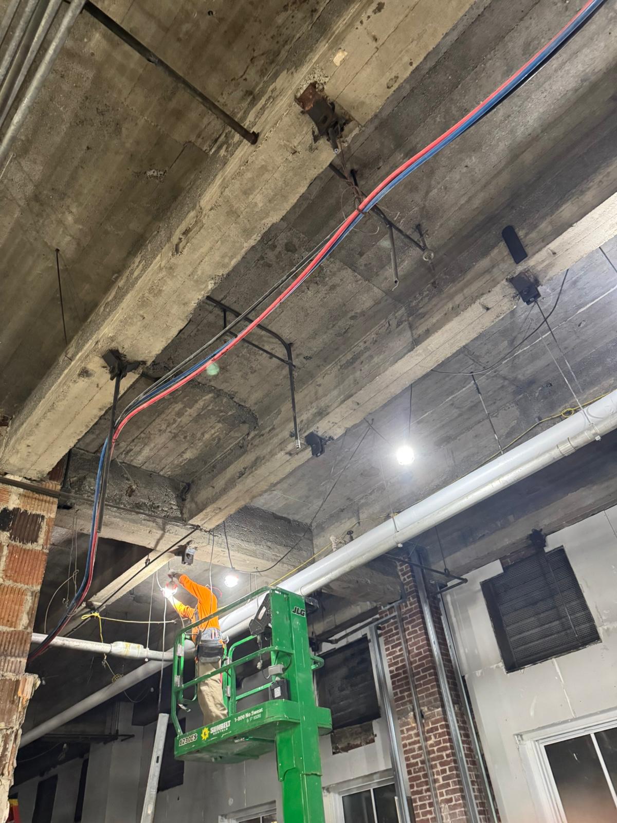 New services run against the original concrete slab, worked from a lift