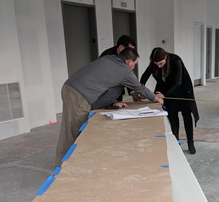 The Integral team at a plan table on site, measuring off the drawing set in a raw floor
