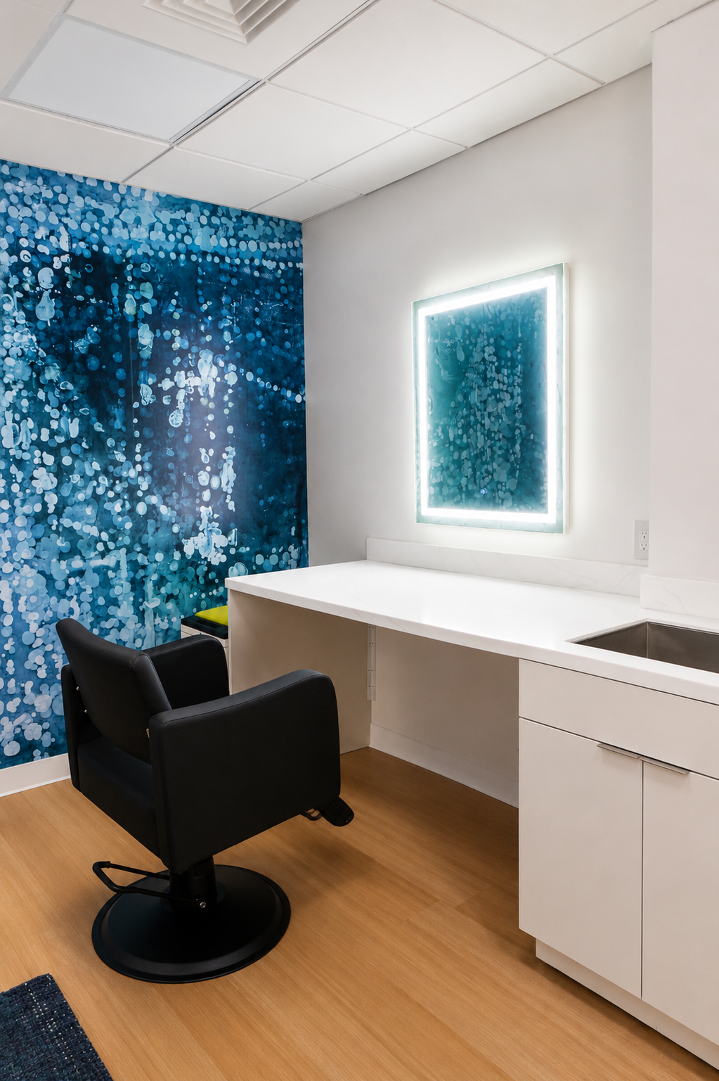 A single styling station: a lit mirror on the wall, counter and undermount sink, CBS Broadcast